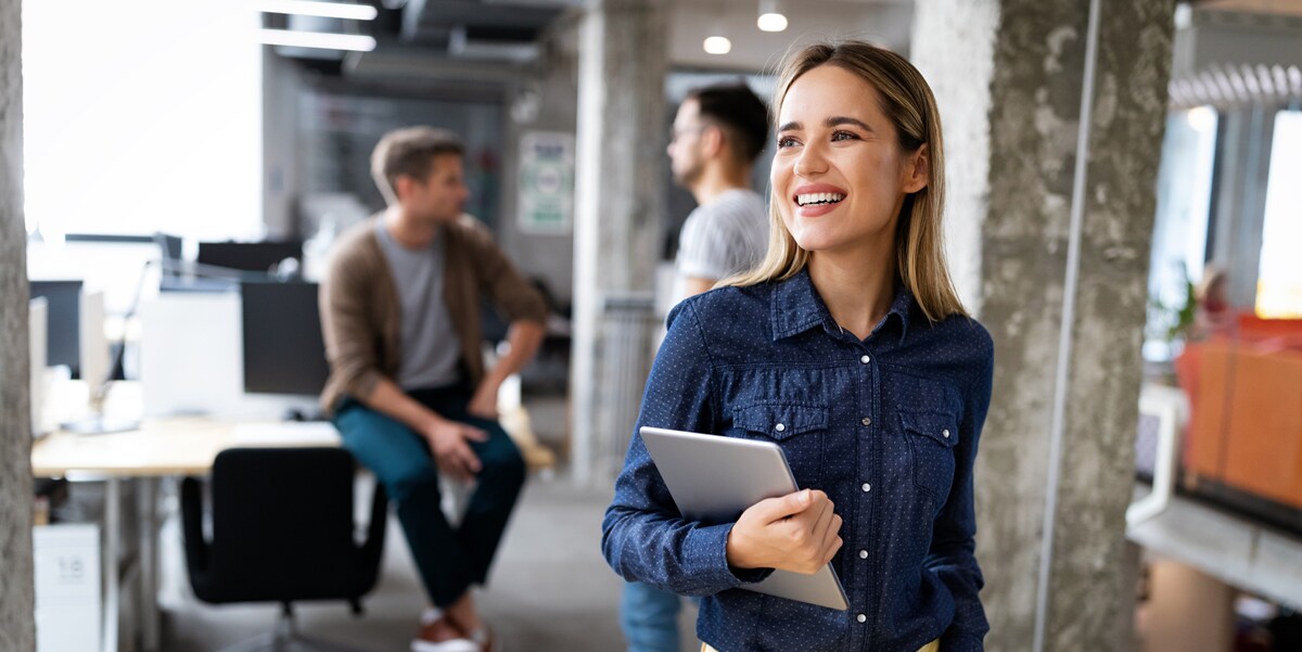 woman walking through office with laptop in arm