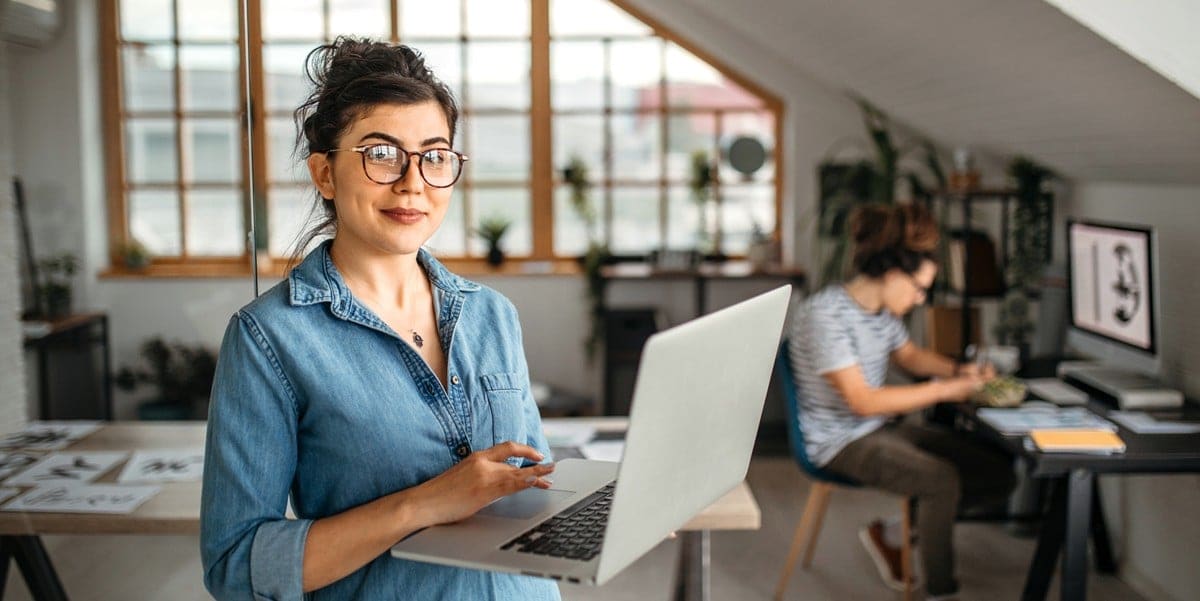 woman in office holding laptop