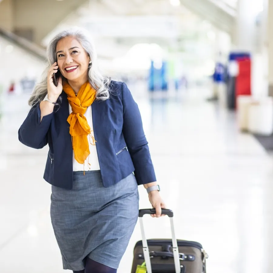 Lady in blue jacket walking through airport with case